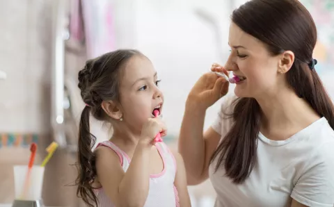 Mother brushing teeth with daughter.