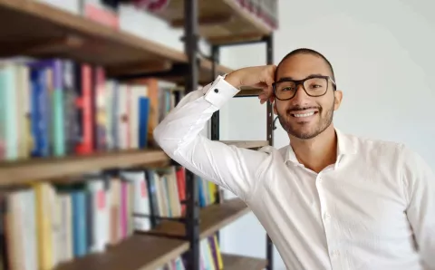 A man next to a bookshelf in a library.