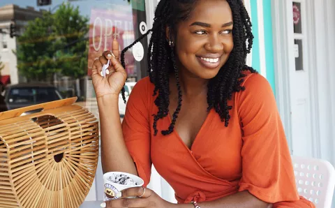 A woman smiling while eating ice cream.