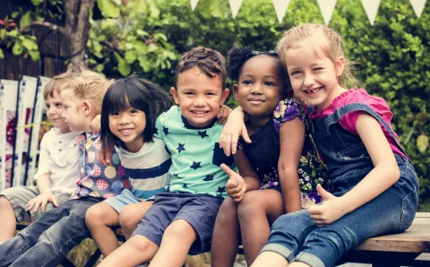 A group of children smiling on a bench.