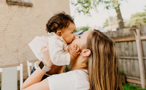 A mother kissing her child.